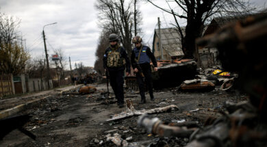 Volunteers of the Territorial Defence Forces walk next to destroyed Russian tanks and armoured vehicles in Bucha