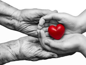 Little,Girl,And,Elderly,Woman,Keeping,Red,Heart,In,Their