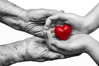Little,Girl,And,Elderly,Woman,Keeping,Red,Heart,In,Their